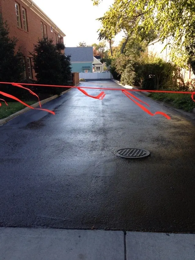 Repaved lane between brick buildings, taped off to cure