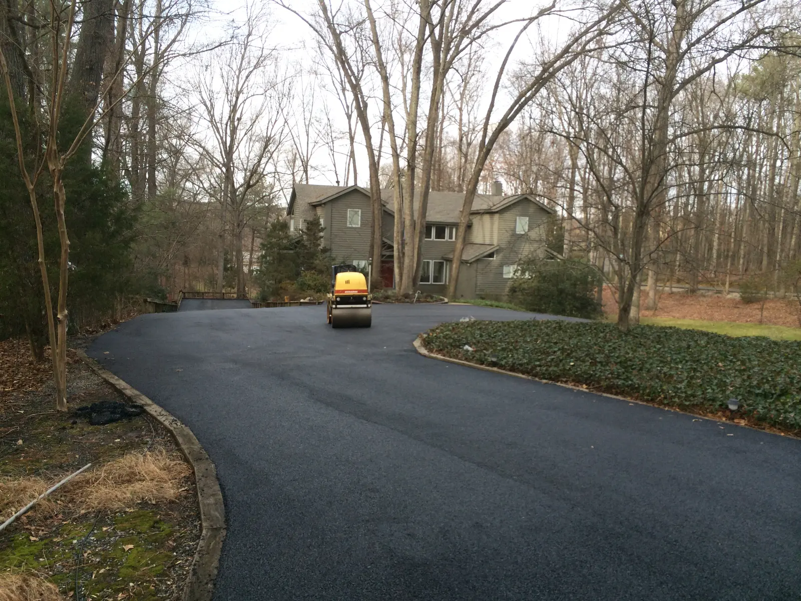 Roller finishing a wooded residential drive in winter