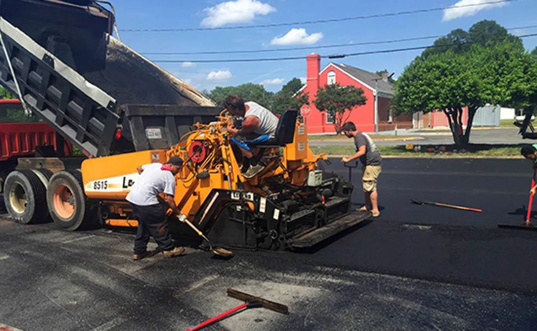 Hand crew screeding hot mix behind the paver